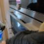 Mrt fönsterputs personal städar rostfri ugn i ett kök.